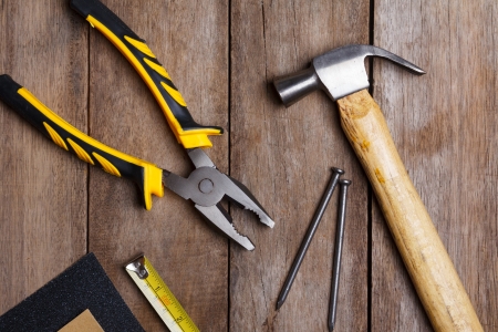 Construction instruments on wooden table - sandpaper, pliers, measuring tape, hammer, nailsの写真素材