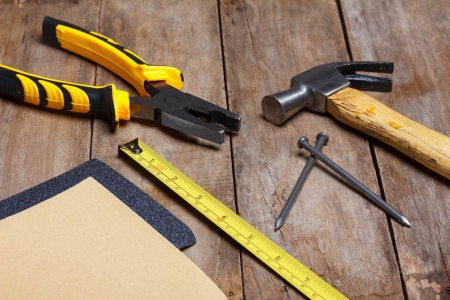 Construction instruments on wooden table - sandpaper, pliers, measuring tape, hammer, nailsの写真素材
