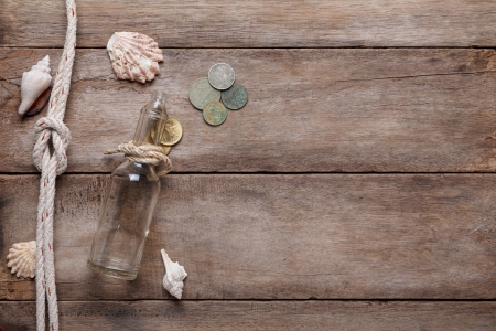 Weathered wooden table with rope, shells, message bottle and vintage coinsの写真素材
