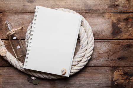 Blank open notebook on sea rope with bottle and ancient coins, on wooden tableの写真素材