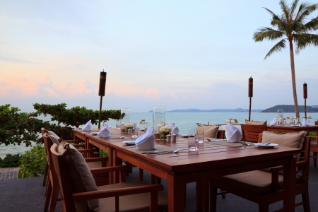 Outdoor restaurant tables, dinner setting at the beach on sunsetの写真素材