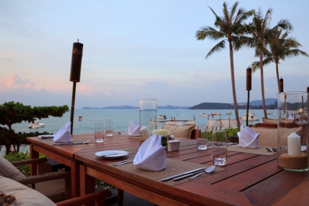 Outdoor restaurant tables, dinner setting at the beach on sunsetの写真素材