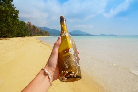 Bottle with a message in hand, on tropical islandの写真素材