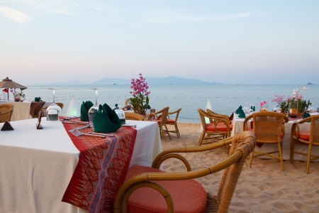 Outdoor restaurant tables, dinner setting at the beach on sunsetの写真素材