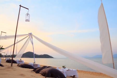 Romantic dinner setting on tropical beach at sunsetの写真素材