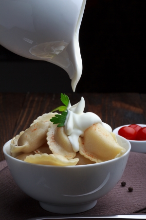 Steamed meat dumplings, pouring sour cream, traditional pelmeni or varenyky dish の写真素材