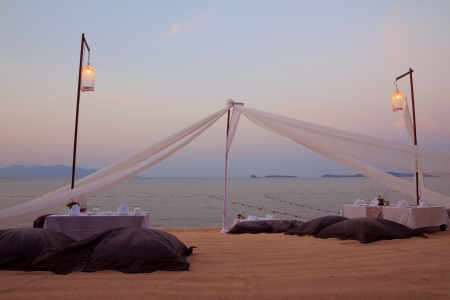 Romantic dinner setting on tropical beach at sunsetの写真素材
