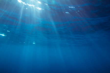 Underwater shot with sunrays in deep tropical seaの写真素材