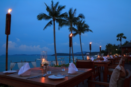 Outdoor restaurant tables, dinner setting on the beach at eveningの写真素材