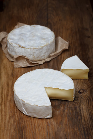 Camembert cheese on old wooden table, focus on first piece centerの写真素材