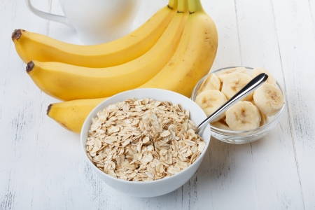 Bowl of oat flakes with sliced banana close-up on wooden tableの写真素材