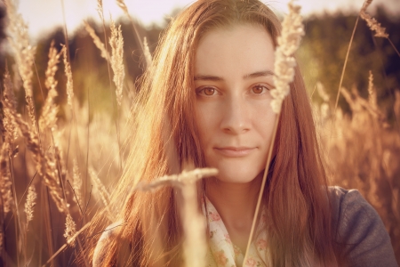 Beautiful girl in sunny autumn field, vintage toned photoの写真素材