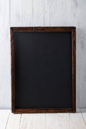 Vintage blank chalkboard on white wooden backgroundの写真素材