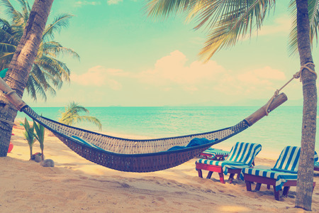 Vintage stylized hammock under palms trees on sunny tropical beachの写真素材