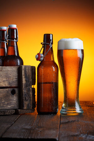 Beer glass and beer crate with bottles on wooden table still lifeの写真素材