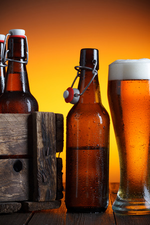 Beer glass and beer crate with bottles on wooden table still lifeの写真素材