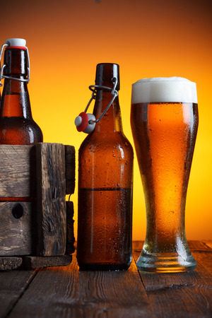 Beer glass and beer crate with bottles on wooden table still lifeの写真素材