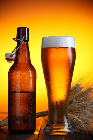 Beer glass and bottle with swing top with wheat bunch on wooden tableの写真素材