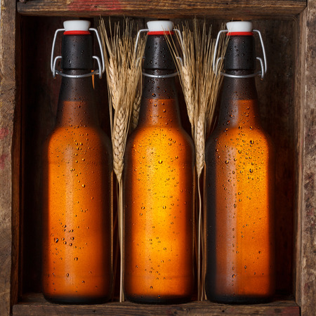 Beer bottles with wheat stems in old wooden crate still lifeの写真素材