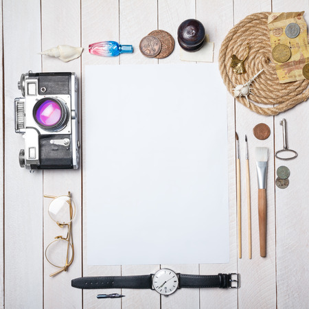 White blank paper sheet with lot of different creative stuff around it on wooden tableの写真素材
