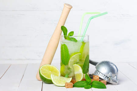 Mojito cocktail on wooden table with lime, mint, sugar, muddler and ice crusherの写真素材