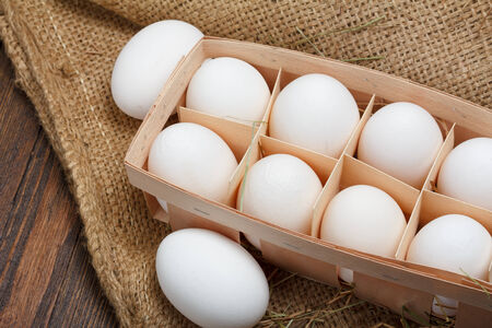Eggs in a wooden box on burlap clothの写真素材