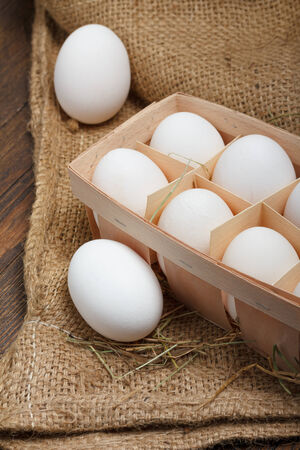 Eggs in a wooden box on burlap clothの写真素材