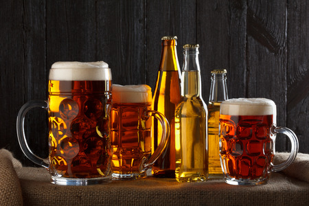 Assortment of beer glasses on table with burlap cloth, dark wooden backgroundの写真素材