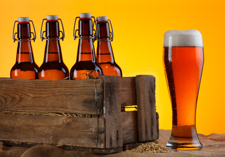 Glass of beer with bottles in crate and barley still lifeの写真素材