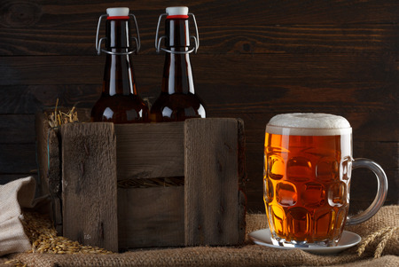 Beer glass with beer bottles in wooden crate on burlap clothの写真素材