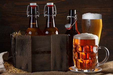 Beer glass and crate with beer bottles on burlap cloth with barley seedsの写真素材