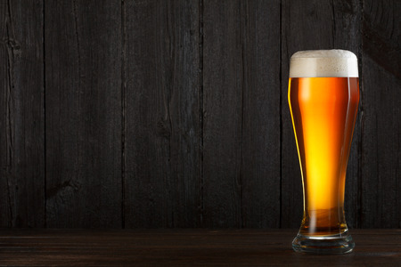 Glass of beer on wooden table, dark background with copy spaceの写真素材