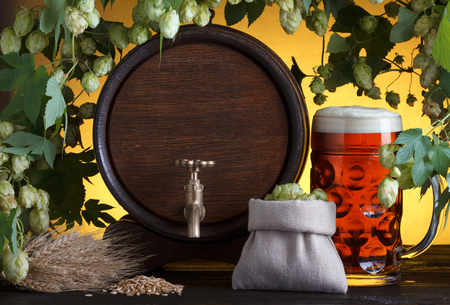 Vintage beer barrel with beer glass and fresh hops, with barley on wooden table still lifeの写真素材