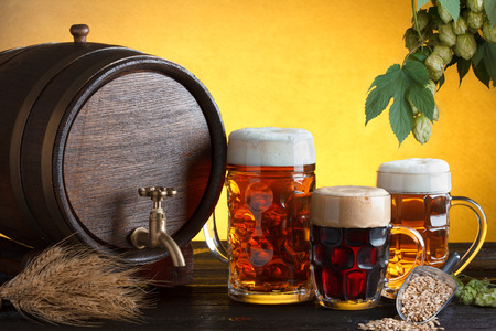 Vintage beer barrel with beer glasses on wooden table with wheat bunch, hop and barley, still life with copy spaceの写真素材