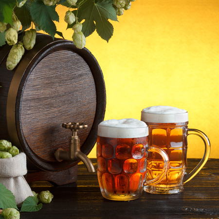 Vintage beer barrel with two beer glasses and frame of fresh hops on wooden table still life, copy spaceの写真素材