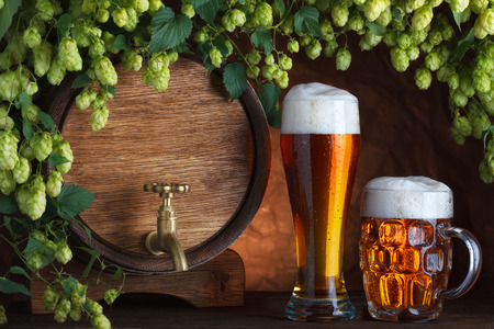 Beer glasses and beer barrel with fresh hops cones still-lifeの写真素材