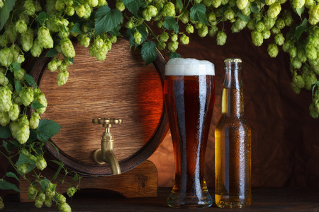 Beer glass and bottle with vintage beer barrel with fresh hops cones still-lifeの写真素材
