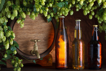 Beer bottles with beer barrel and fresh hops frame still-lifeの写真素材