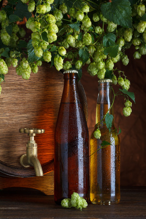 Beer bottles with beer barrel and fresh hops frame still-lifeの写真素材