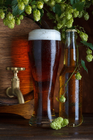Glass of beer with barrel, bottle and fresh hops still-lifeの写真素材