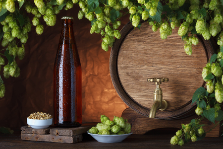 Beer bottle with vintage beer barrel with fresh hops cones with barley still-lifeの写真素材