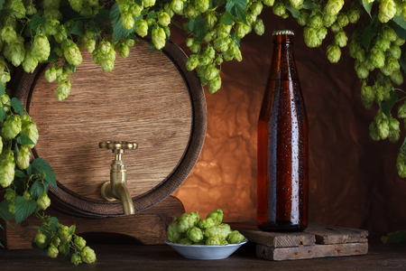 Beer bottle with vintage beer barrel with fresh hops cones still-lifeの写真素材