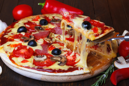 Pizza slice with melted cheese on lifterの写真素材
