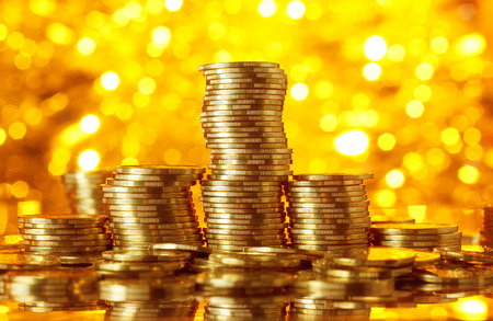 Golden coins stacks on bright light glowing bokeh background, business finance wealth and success conceptの写真素材