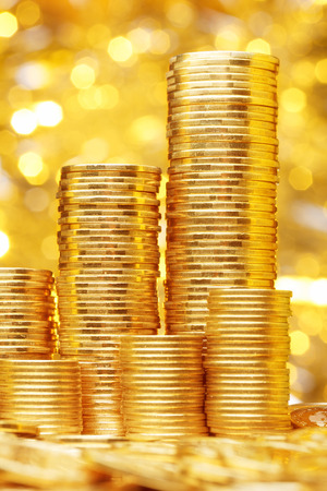 Sparkling new golden coins stacks on bright light glowing bokeh background, business finance wealth and success conceptの写真素材