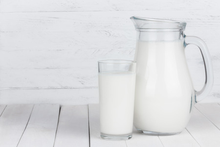 Glass of organic milk and full jar on white wooden table still lifeの写真素材