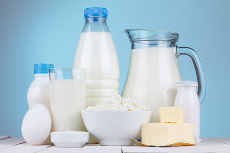 Natural organic dairy products, milk, cottage cheese, eggs, butter, yoghurt, butter and sour cream on white wooden bale and blue background still lifeの写真素材