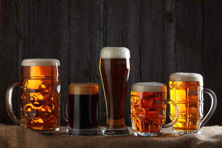 Beer glasses with lager, dark lager, brown ale, malt and stout beer on table, dark wooden backgroundの写真素材