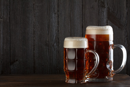 Beer glasses on table, dark wooden background with copy spaceの写真素材