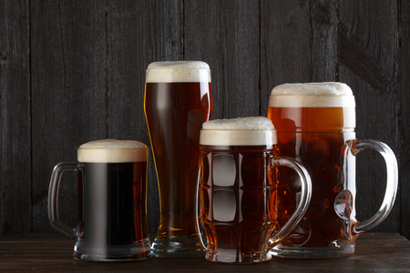 Beer glasses with lager, dark lager, ale, stout beer on table, dark wooden backgroundの写真素材